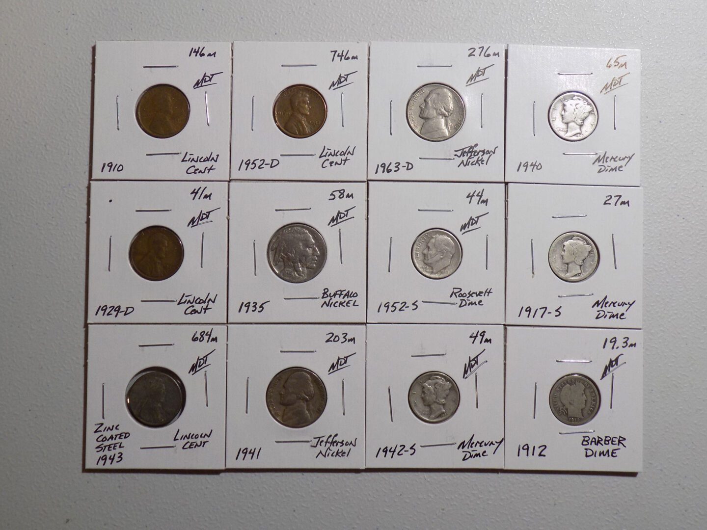 A group of coins are shown on a white surface.