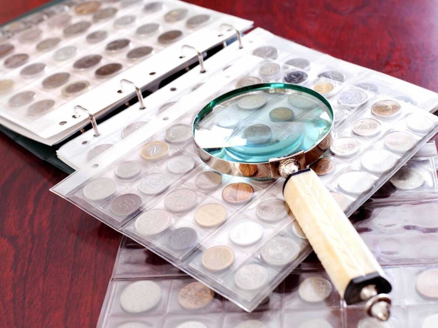 A magnifying glass sits on top of a stack of coins.