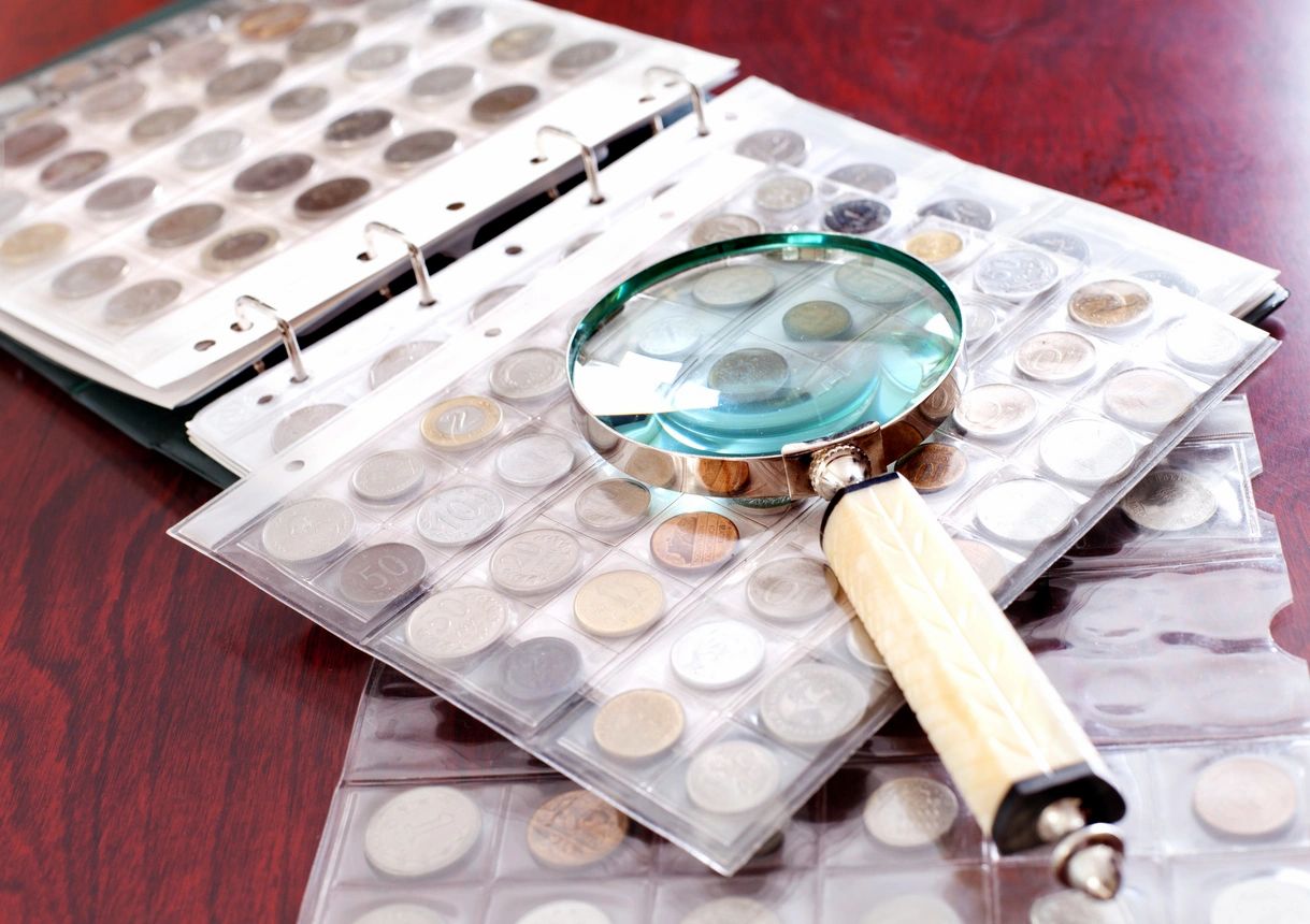 A magnifying glass sits on top of a stack of coins.