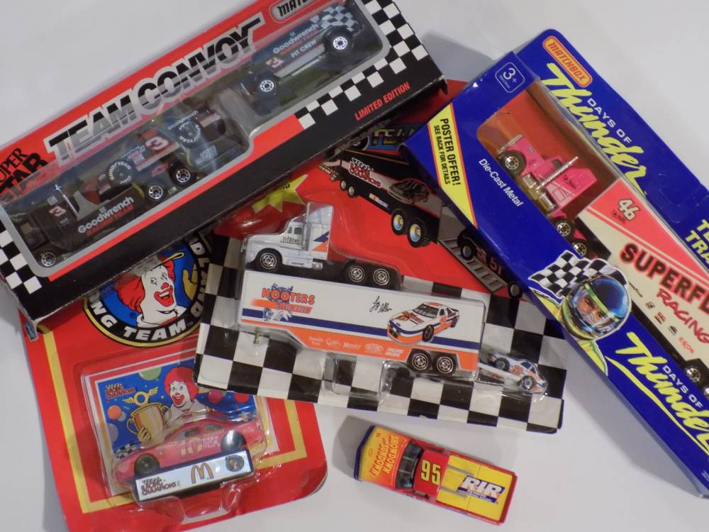 A group of toy cars and trucks on a white surface.