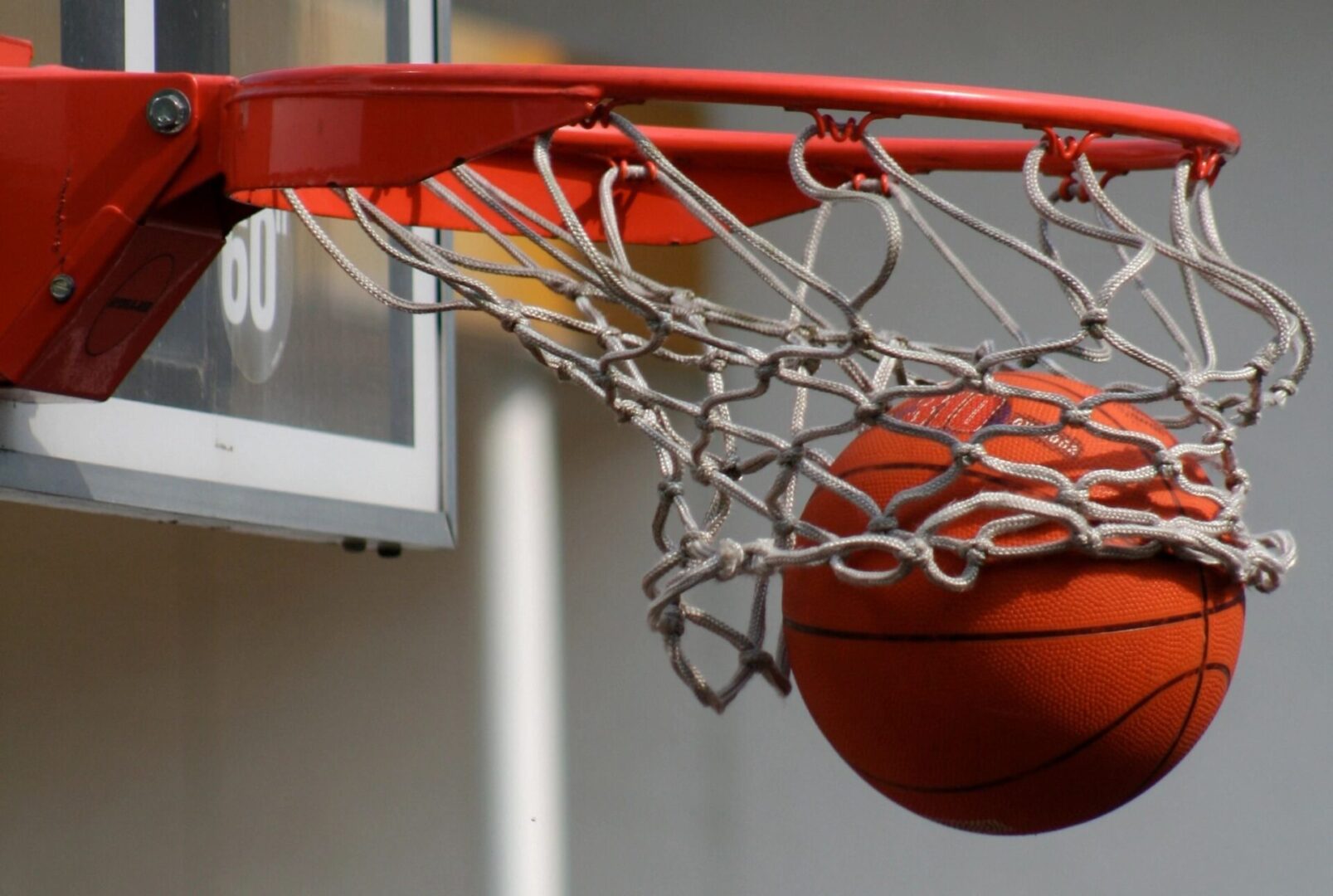 A basketball is going into the hoop of a basketball hoop.