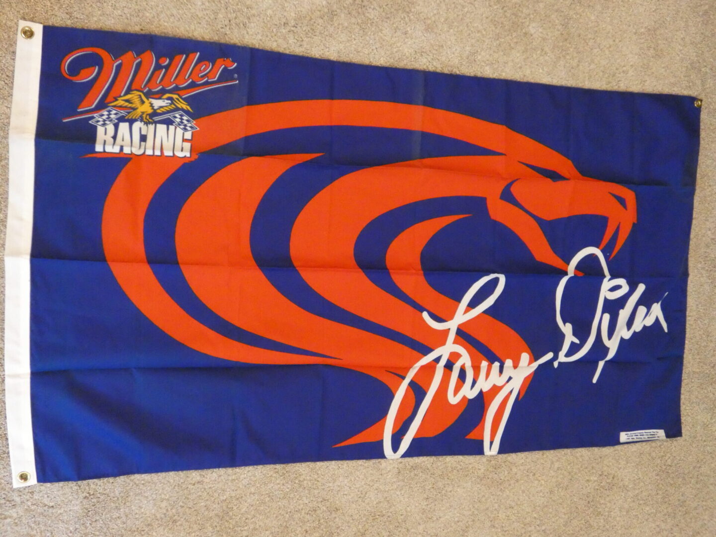 Blue Miller Racing flag with red snake and signature.