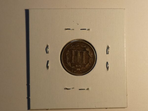 Three cent US coin on white card.