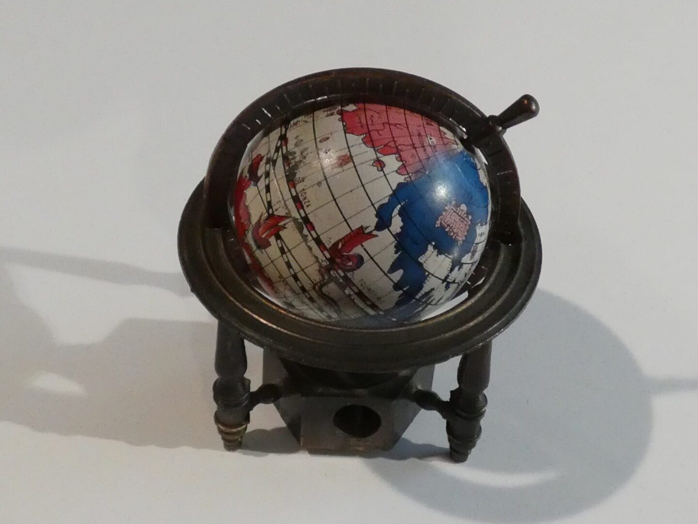 Globe shaped pencil sharpener on a stand.