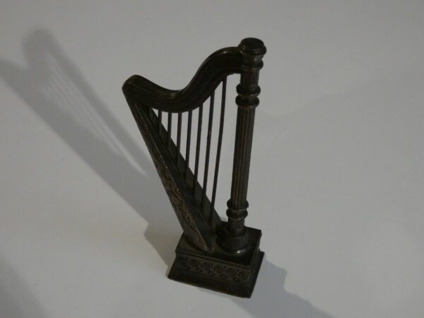 Ornate metal harp figurine on white background.