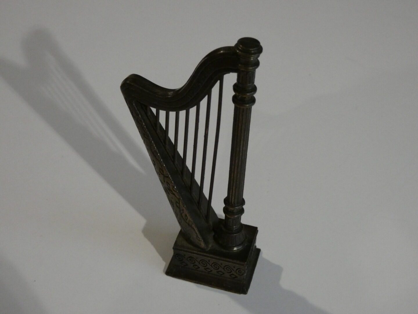 Ornate metal harp figurine on white background.