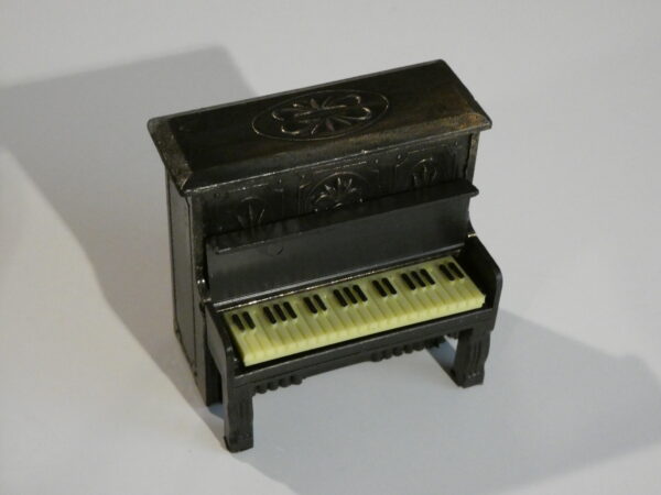 Black miniature piano with white keys.