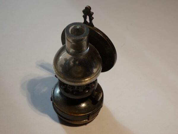 Antique metal pencil sharpener shaped like a lamp.