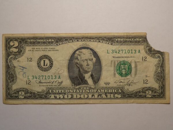 Two dollar bill with a torn corner.