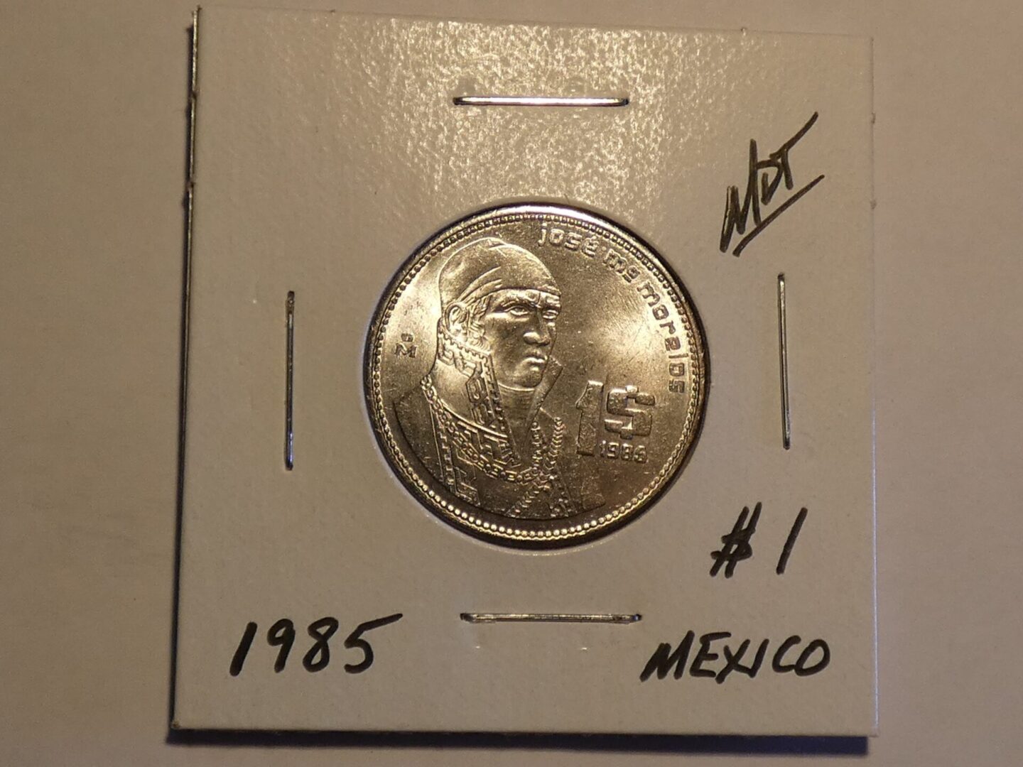 1985 Mexican coin with a man's face.